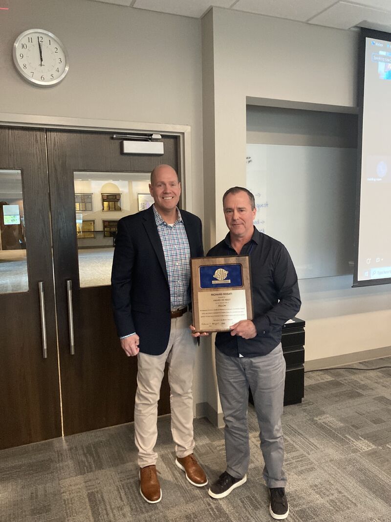Two men, one of whom is Rick Rosati, standing together. Rick holds an award 