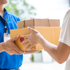 a man in a blue shirt delivering a package to a woman in a white shirt