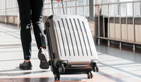 a person in a suit pulling a suitcase 