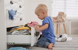 child opening the bottom drawer of a white dresser