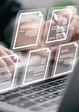person working on computer with document icons floating over the keyboard