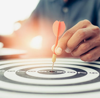 person putting dart into the bullseye of the dart board